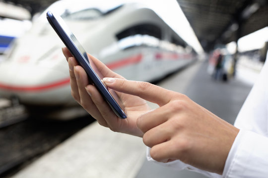 Close up of hands woman using her cell phone at a station platfo