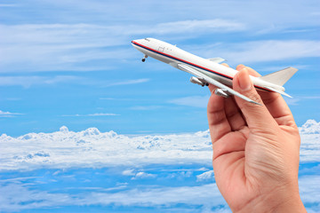 woman hand holding a model plane on blue sky and white cloud bac