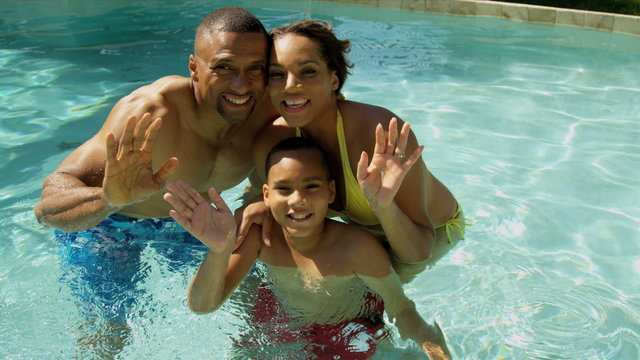 Happy Ethnic Vacation Family Swimming Pool Waving Camera