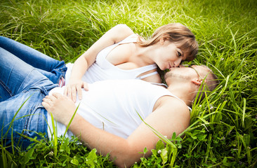 Sexy girl kissing her boyfriend on grass
