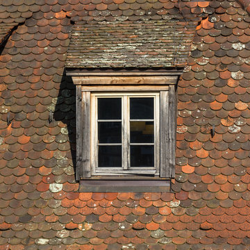 Window of attic on old tiled roof.