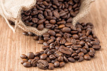 Coffee beans in coffee bag made from burlap on wooden