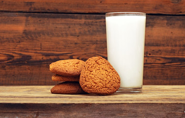glass of milk and oat cookies on wooden background