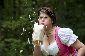 Junge Frau in Dirndl hat Spaß mit Bier