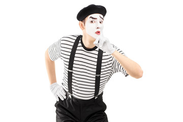 Male mime artist gesturing silence with a finger on his mouth