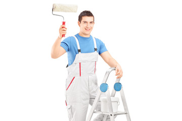 Male painter holding a roller and standing on a ladder