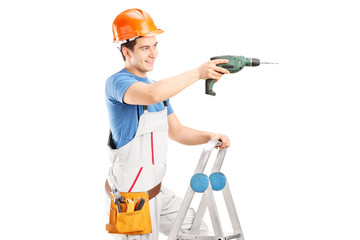 Repairman with a drilling machine on a ladder