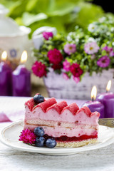 Pink layer cake decorated with fresh fruits on wooden table