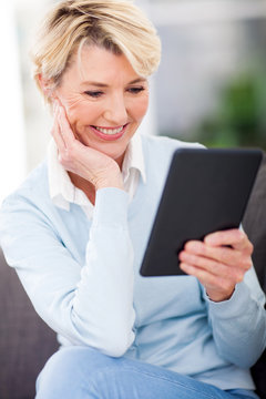 mature woman reading a book on tablet computer