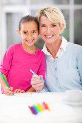 little girl with her grandmother drawing at home