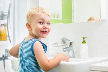 kid boy washing his face and hands in bathroom - obrazy, fototapety, plakaty