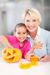 Obraz na płótnie Canvas little girl and grandmother making halloween pumpkin