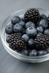 Close-up of glass bowl full of ripe blackberries and blueberries