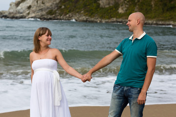 Pregnant woman and her husband by the sea.