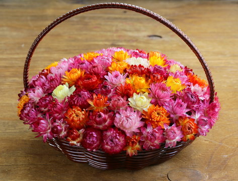 wicker basket with multicolored flowers on wooden table