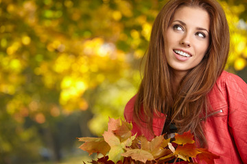 Beautiful elegant woman standing in a park in autumn