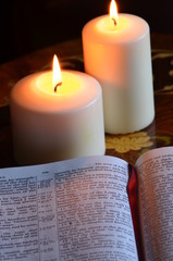 Student studyinhg holy bible by candlelight