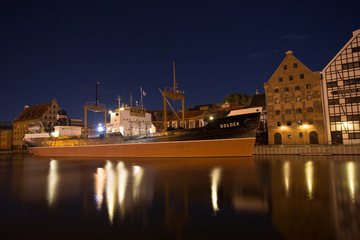 Fototapeta na wymiar Reflections of the ship Soldek at night in the river Motlawa in