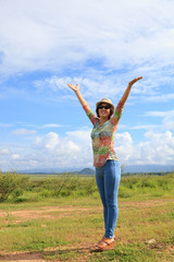 Fototapeta premium young asian woman standing in field and rising up hand