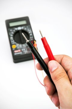 Multimeter with black and red wire in hands