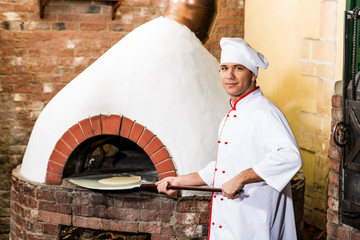 Chef puts dough in the oven for pizzas,