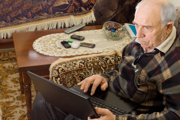 Naklejka na ściany i meble Senior man sitting working on a laptop