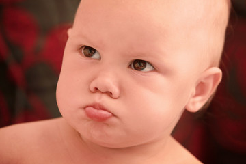Funny angry Caucasian baby girl close-up portrait