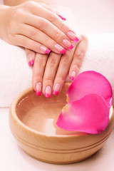 Obraz na płótnie Canvas pink manicure with fragrant rose petals and towel. Spa