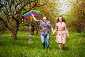 Happy couple are fling  kite on a spring meadow
