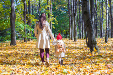 Back view of young mother and her cute little daughter walking