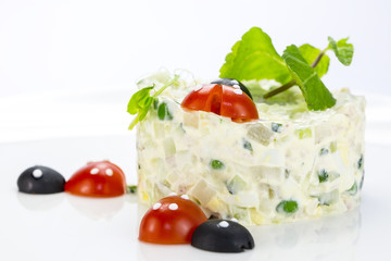 Olivier salad decorated with tomato in the shape of ladybugs