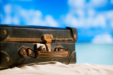 Obraz na płótnie Canvas old retro antique suitcase on beach, sea and sky backgound