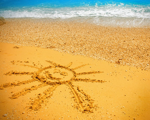 Drawing of the smiling sun on sand