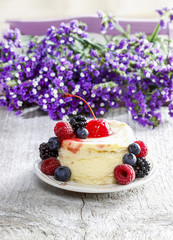 Round cake with fresh fruits. Purple flowers in the background.