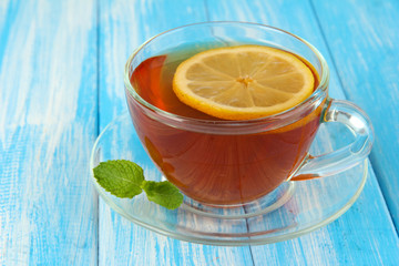 Cup of tea with lemon on table on blue background