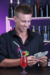 Portrait of handsome barman receiving tips from client