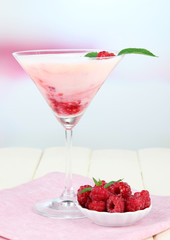 Raspberry milk dessert in cocktail glass, on light background