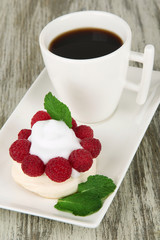Tasty meringue cake with berries and cup of coffee,