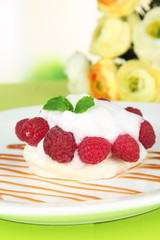Tasty meringue cake with berries on green wooden table