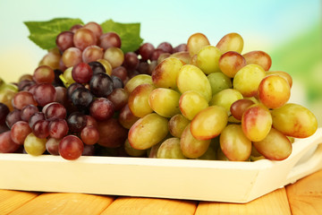 Fresh grape on wooden tray on bright background