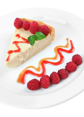 Slice of cheesecake with raspberry on plate, isolated on white