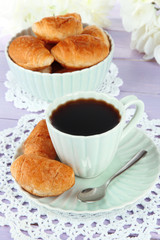 Tasty croissants and cup of coffee on table close-up