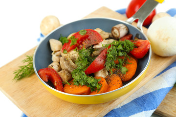 Sliced fresh vegetables in pan on wooden board isolated on
