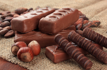 Delicious chocolate bars with cocoa beans and nuts close up