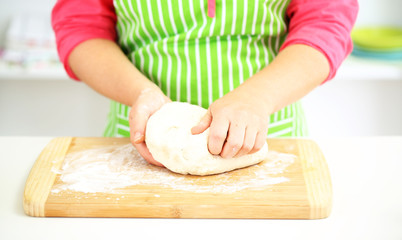 Obraz na płótnie Canvas Female hands in flour closeup kneading dough on table