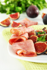 Tasty figs with ham on white wooden table