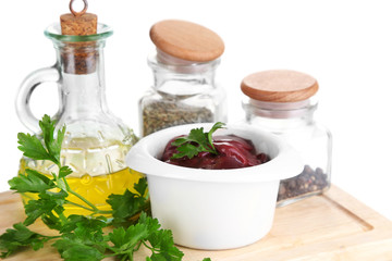 Raw liver in bowl with spices and condiments isolated on white