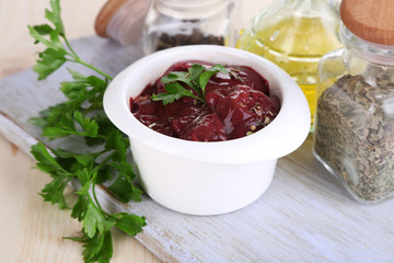 Raw liver in bowl with spices and condiments