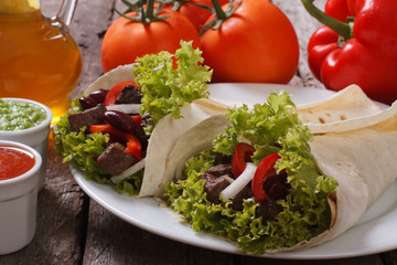 burrito with beef and vegetables and sauce on the table