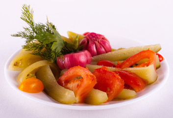 огурцы, помидоры, чеснок и зелень на тарелке